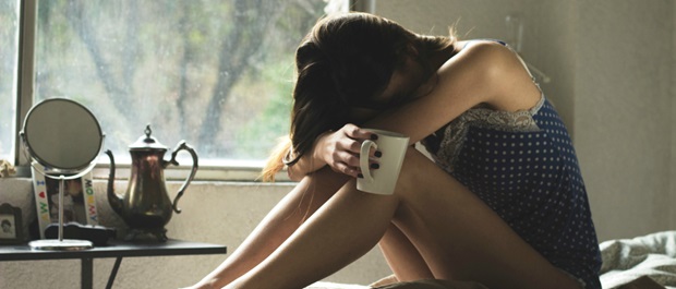 Woman upset holding a coffee mug in bed