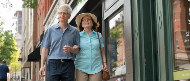 Older couple walking along storefronts