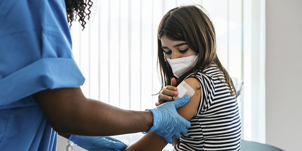 A young girl wearing a mask getting an immunization