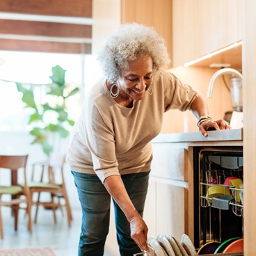 Eldery woman using her dishwasher.